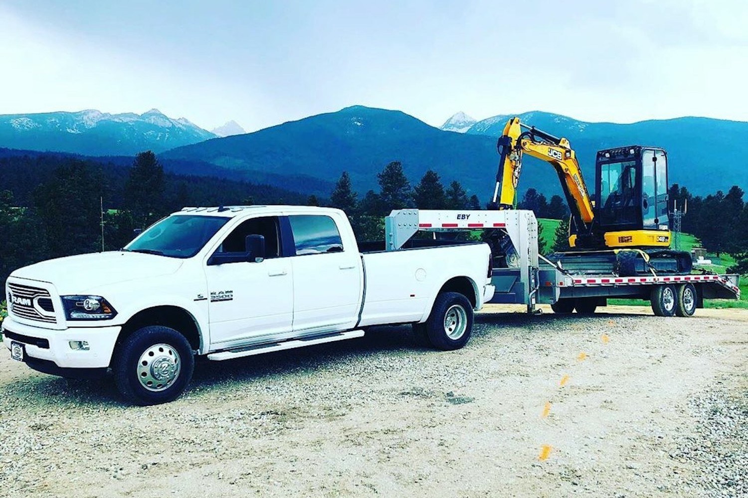 Pickup truck towing an equipment trailer carrying an excavator